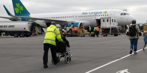 Image of passenger being assisted to the aircraft in a wheelchair